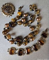 Full view of brooch, necklace and bracelet showing design and colors