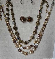 Overview of two necklaces and earrings displayed on jewelry stand