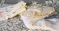Stack of folded crochet doilies, pillowcases and table topper on lace background