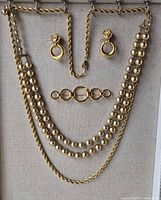 All four jewelry pieces displayed: rope chain, bead necklace, brooch, earrings