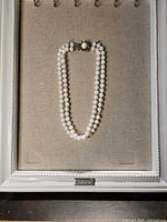 Full view of double strand coral bead necklace on display board