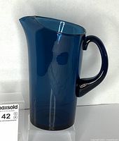 Front view of cobalt blue glass pitcher showing handle and spout