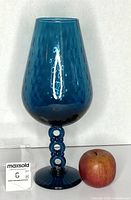 Full view of blue Empoli footed vase next to apple for scale