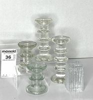 All five clear glass candle holders of varying heights displayed
