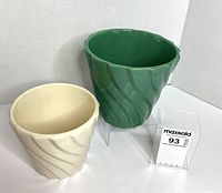 Green and white ceramic swirl planters side by side