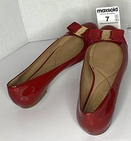 Top view of both red patent leather flats showing bows and logo hardware