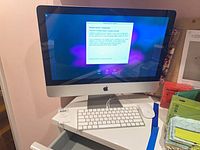 Front view of Apple iMac displaying setup screen with keyboard and mouse