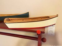 Rowboat model displayed on red wall shelf