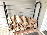 Full view of black metal log holder with sample firewood loaded