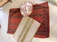 Overview of all three items: red area rug, striped rug, round coral pillow