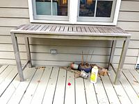 Front view of rectangular slatted wooden patio table on deck