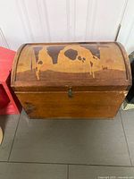 Front view of wooden trunk with cow design and latch