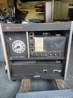 Front view of Bell Industries 2000 cabinet showing clock face, control panel, speaker grille, knobs, and lower power section