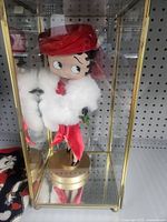 Figurine inside clear case showing red dress, white stole