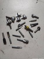 All eighteen router bits laid out on white surface
