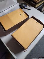 Two opened brown boxes filled with clasp envelopes