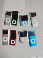 Front view showing eight iPod Nano units, colour and screen types visible