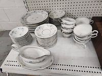 All stacked plates, cups and gravy boat showing pattern and quantity