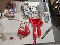 All components laid out including console, controllers, cables, stand, game case