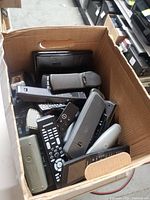 Top view of bankers box showing numerous mixed remote controls