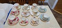 All 11 teacup and saucer sets arranged on table