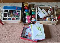Overview of boxed glass ornaments, loose ornaments in tray, greeting cards in two boxes