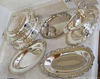 Group of silver-plated serving pieces showing all items together: covered dish components, gravy boat, various platters