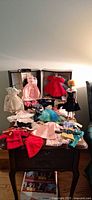 Overall view of Barbie doll, open carrying case and spread of vintage outfits on table