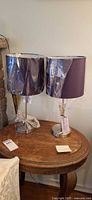 Pair of new table lamps with purple shades on wooden table