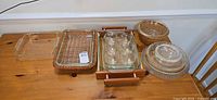 All items displayed on table showing glass bakeware, bowls, pie plates, tray and baskets