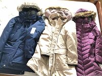 All three coats laid out: navy, beige, plum