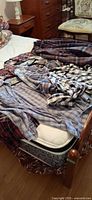 Multiple plaid shirts and fleece jacket laid on bed