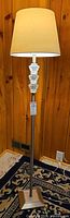 Full view of floor lamp illuminated, showing shade, pole, base