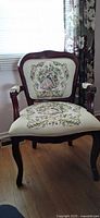 Front view of upholstered Rococo style armchair showing tapestry seat and back, carved wood frame