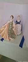 Two Royal Doulton lady figurines side by side