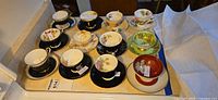 Overview of 12 teacup and saucer sets arranged on counter