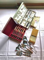Overview of boxed carving set, steak knives, small knives, and loose serving utensils