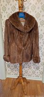 Full front view of muskrat fur coat on stand
