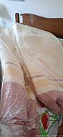 Two folded wool blankets in plastic on bed