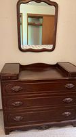 Front view of dresser showing three drawers, side compartments, and mirror
