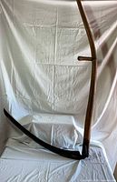 Full view of scythe showing wooden snath, blade and both grips