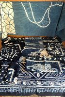 Overall lot showing large shibori tablecloth draped and stacked indigo batik linens