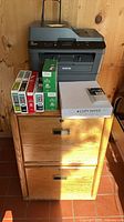 Printer on top of oak cabinet with cartridge boxes and paper