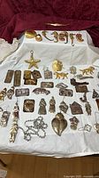Overview of assorted metal Milagros, gold seahorses, prisms on cloth