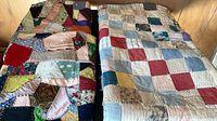Two of three quilts folded on surface, showing crazy quilt left and patchwork quilt right