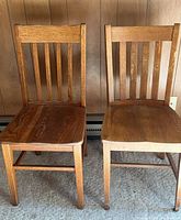 Front view of both oak chairs showing slat backs and seats