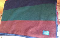 Full view of folded Pendleton wool blanket showing navy, green, brown, red stripes