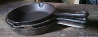 Side view of all three stacked skillets showing graduated sizes and handle style