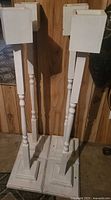 Front view of four white wooden pedestal stands showing full height and bases