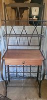 Front view of full baker's rack showing iron frame, wooden drawer, shelves